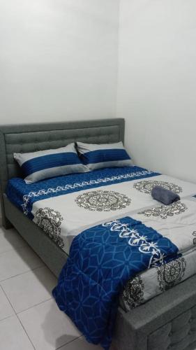 a bed with blue and white sheets on it at MAS'homestay perlis in Kangar