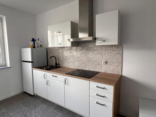a kitchen with white cabinets and a white refrigerator at Noclegi - Pokoje - STEMPO in Skarżysko-Kamienna