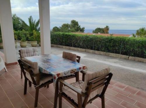 a table and chairs on a patio with a view of the ocean at Bellavista Apartments in Scopello