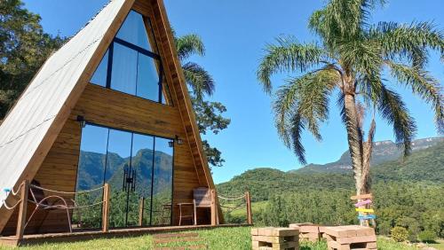a cabin with a palm tree and mountains in the background at Vista dos Canyons in Praia Grande