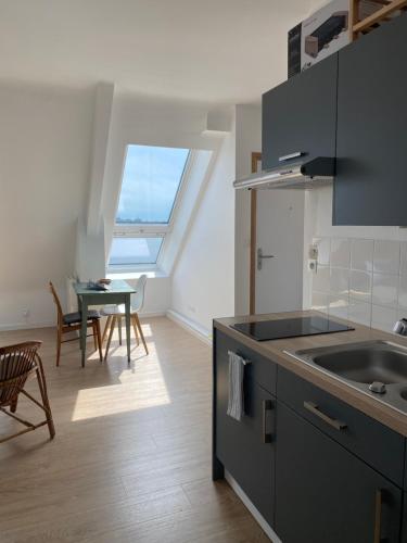 a kitchen with a sink and a table with chairs at PANORAMA du LOC in Locmiquélic