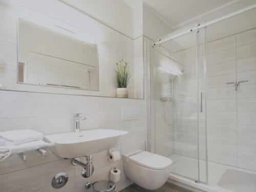 La salle de bains blanche est pourvue d'un lavabo et d'une douche. dans l'établissement Ferienwohnung Strandkorb, à Dierhagen