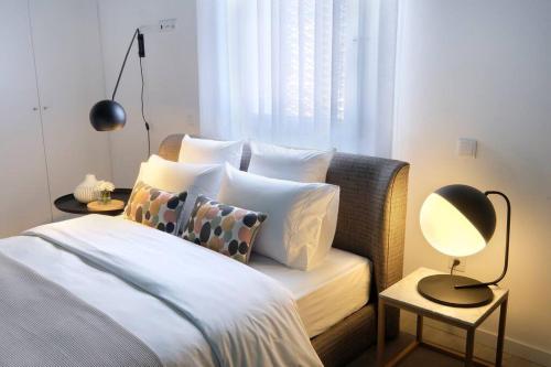 a bedroom with a bed with white pillows and a lamp at Retiro do Moliceiro in Aveiro
