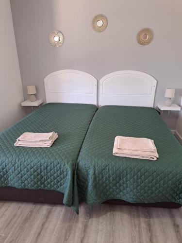 a bedroom with two beds with green sheets and towels at Sea, Sun and Wild Nature in Costa de Santo André