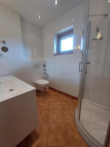 uma casa de banho com um chuveiro, um WC e uma janela. em Apartment Kofelblick em Unterammergau