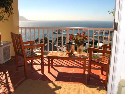 a balcony with a table and chairs and the ocean at Albatross Guest House in Simonʼs Town