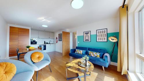 uma sala de estar com um sofá azul e uma mesa em Water View Apartment- 2 Bed - Cardiff Bay - Free Parking!! em Cardiff