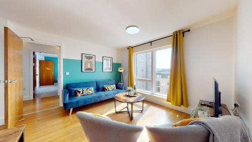 a living room with a blue couch and a table at Water View Apartment- 2 Bed - Cardiff Bay - Free Parking!! in Cardiff