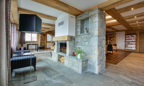 a living room with a stone fireplace and a tv at CGH Résidences & Spas Chalet Les Marmottons in La Rosière