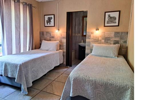 a bedroom with two beds and a window at Lion King in Marloth Park
