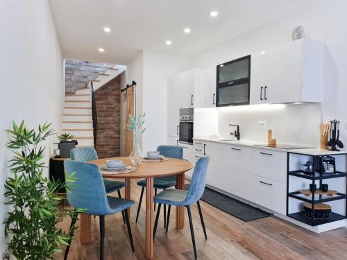 uma cozinha com uma mesa de madeira e cadeiras azuis em CASA OFICINA - Praia & Centro (300m) - WiFi - AC em Carvoeiro