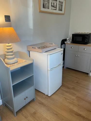 a room with a table with a lamp and a refrigerator at Cove Cott in Warsash