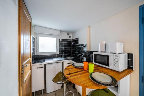 a small kitchen with a wooden table with a microwave at Charming Studio of 17 m with garden Montpellier in Montpellier