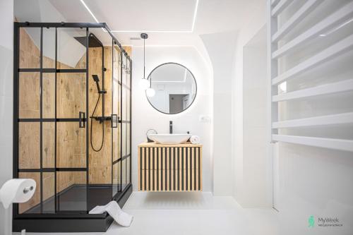 a bathroom with a shower with a sink and a mirror at Apartament w Rynku I, MyWeek in Radków
