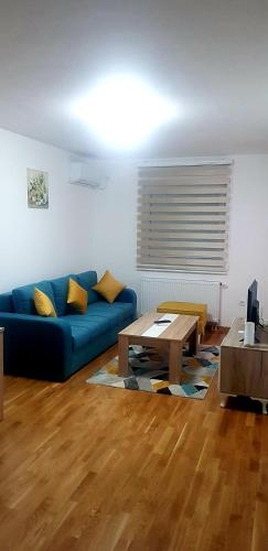 a living room with a blue couch and a table at Stan na dan CENTAR 7 in Doboj