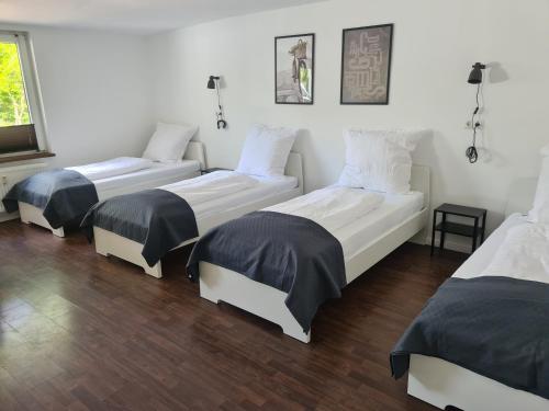 three beds in a room with wood floors at Pension An der Mühle in Sottrum