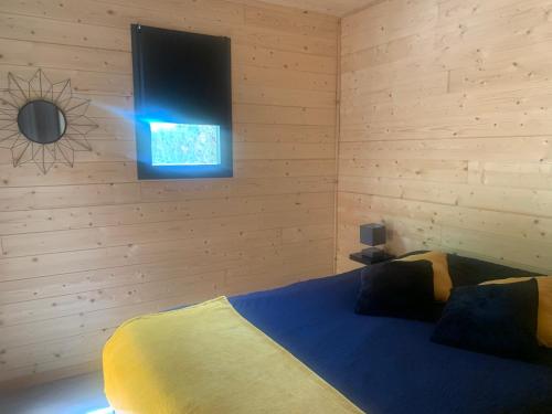 une chambre avec un lit avec une télévision au mur dans l'établissement Chalet 1 contemporain dans son écrin de verdure, à Montauban