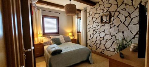 a bedroom with a bed and a stone wall at Villa Salena with pool Slatine in Slatine