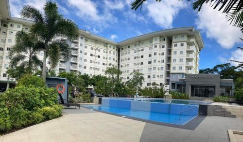 a large building with a swimming pool in front of it at Staycation AMAIA SJDM in Tunkong Manga