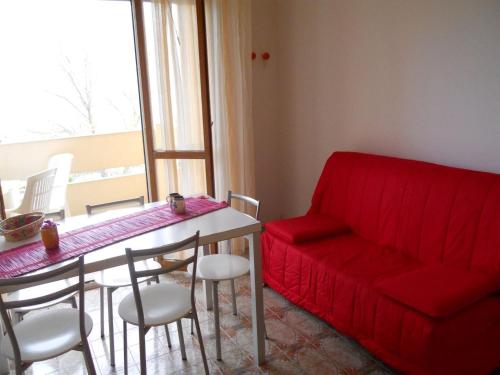 sala de estar con sofá rojo y mesa en Flat with terrace near the beach - Beahost, en Bibione
