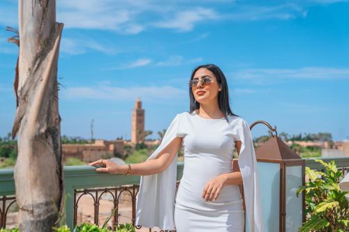 a woman in a white dress standing on a balcony at Riad Lalla Mimouna in Marrakech