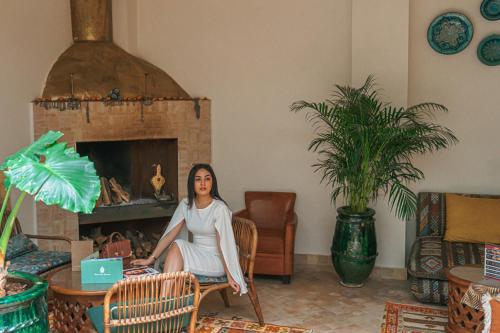 a woman sitting in a living room with a laptop at Riad Lalla Mimouna in Marrakech