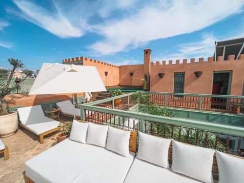 un balcón con muebles blancos y un edificio en Riad Lalla Mimouna en Marrakech