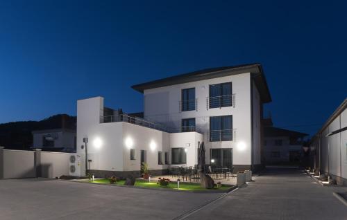 a white building with a parking lot at night at VULCANO Guesthouse in Vinica