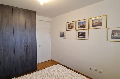 a bedroom with a wooden cabinet and pictures on the wall at Apartman Mima in Zagreb