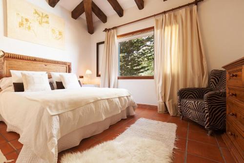 ein Schlafzimmer mit einem Bett, einem Fenster und einem Stuhl in der Unterkunft Font in Mancor del Valle