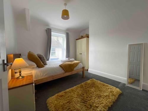 a bedroom with a bed with a rug and a window at Modern 2 BR Flat in Town Centre in Aberystwyth