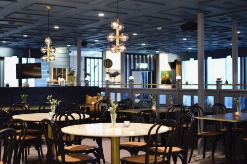 un comedor con mesas, sillas y ventanas en Vättersmålen Stuga, en Gränna