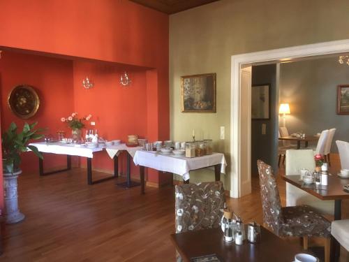 een eetkamer met witte tafels en stoelen en rode muren bij Villa Dorothea in Heringsdorf