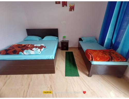 2 Betten in einem Zimmer mit blauen Vorhängen in der Unterkunft AK resort, Barkot in Barkot