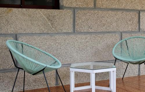two chairs and a table in front of a wall at Altos de Baiona in Baiona