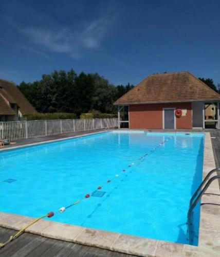 une grande piscine bleue avec un bâtiment en arrière-plan dans l'établissement Bel F3 en résidence avec piscine, baignoire balnéo, à Touques