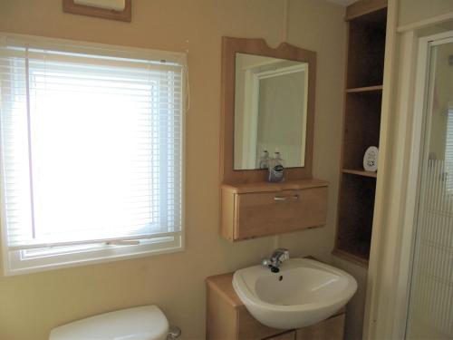 a bathroom with a sink and a toilet and a mirror at 6 Berth heated on The Chase (Albany II) in Skegness