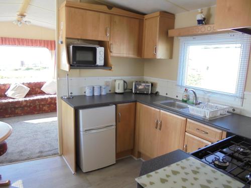a small kitchen with a sink and a microwave at 6 Berth heated on The Chase (Albany II) in Skegness