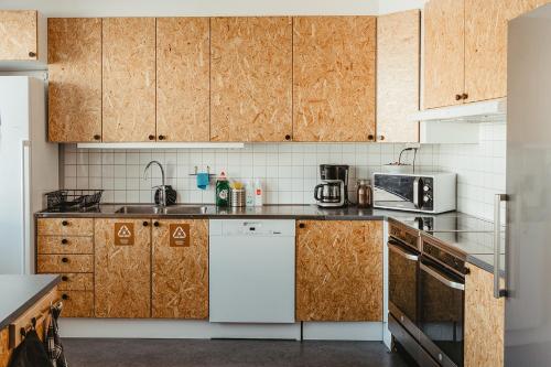 a kitchen with wooden cabinets and a white refrigerator at Norrland YMCA Hostel Umeå in Umeå