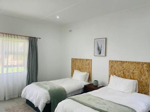 a hotel room with two beds and a window at Ultra modern 2 bedroomed apartment - 2082 in Bulawayo