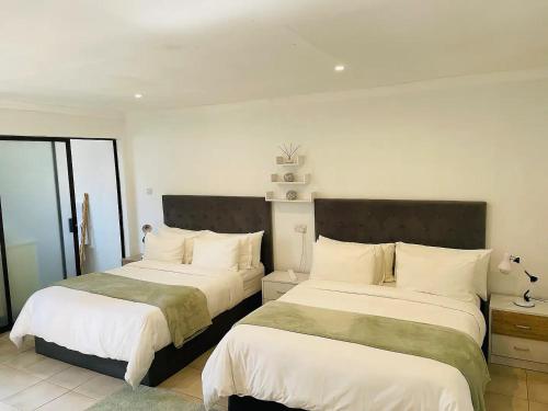- une chambre avec 2 lits et des draps blancs dans l'établissement Mellow 2 bedroomed cottage - 2083, à Bulawayo