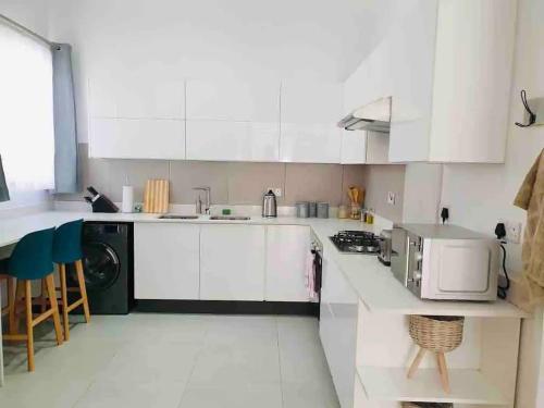 a kitchen with white cabinets and a sink and a microwave at Contemporary 2 bed in Suburbs - 2080 in Bulawayo