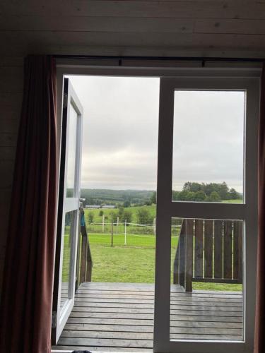 an open door to a porch with a view of a field at Pipowagen Monceau-en-Ardenne in Bièvre
