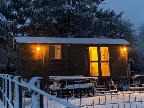 a small cabin in the snow with lights on at Pipowagen Monceau-en-Ardenne in Bièvre