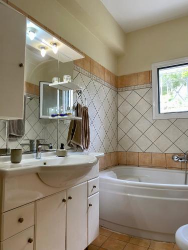 a bathroom with a tub and a sink and a bath tubermottermott at Olive Garden House in Ágios Prokópios