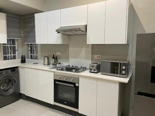 a kitchen with white cabinets and a stove and a microwave at Modern Apartment - 2081 in Bulawayo