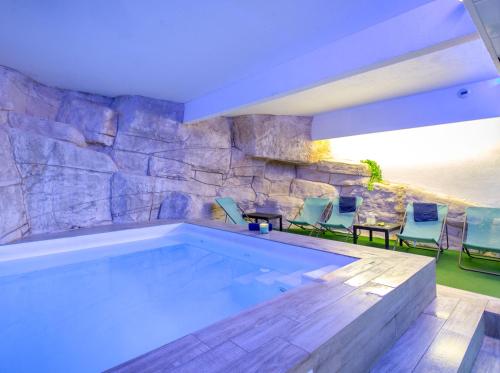 una piscina con sillas y una pared de piedra en SOWELL RESIDENCES New Chastillon, en Isola 2000