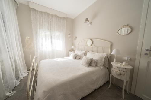 una camera bianca con un letto bianco e una finestra di Bnbook Maison Charlotte Lago Maggiore a Porto Valtravaglia