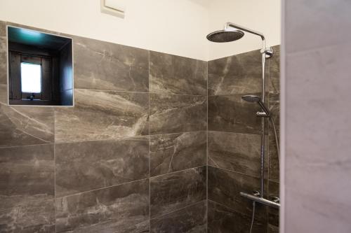 a bathroom with a shower with brown tiles at Landgoed Dennenholt - 5 unique holiday homes in Vierhouten