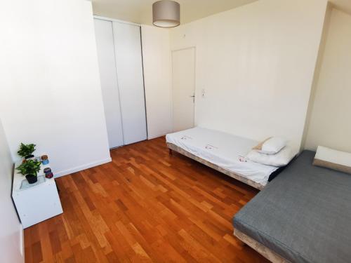 a small bedroom with a bed and a wooden floor at Versailles Trip Appartement in Buc